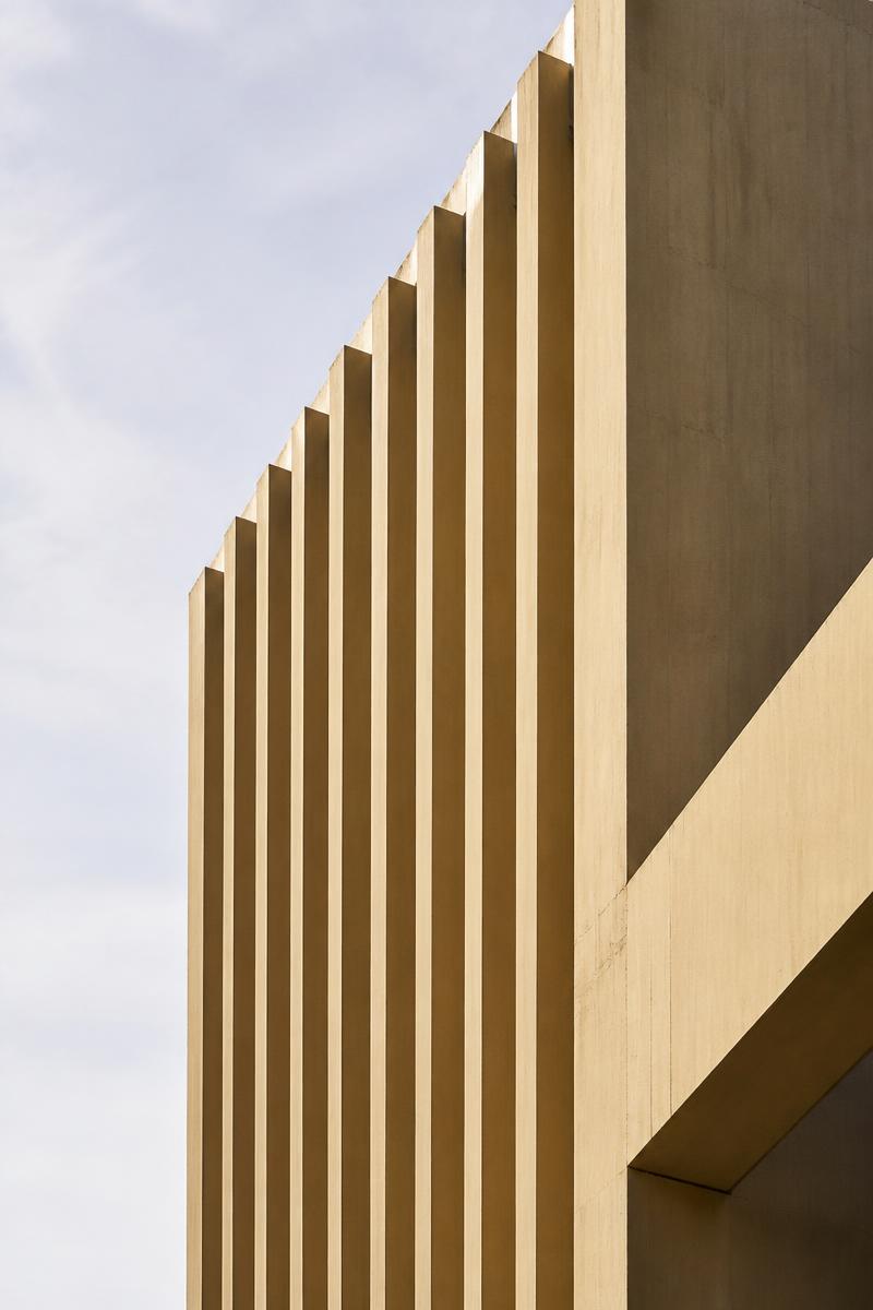 Concrete facade with vertical fins in warm daylight
